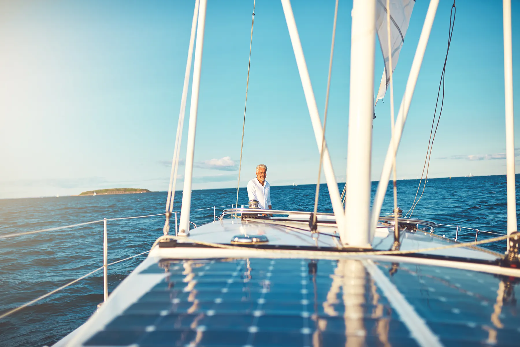 Smiling Mature Man Standing On The Rear Deck Of His Boat While Out For A Sail Along The Coast Smiling Mature Man Standing On The Rear Deck Of His Boat While Out For A Sail Along The Coast
