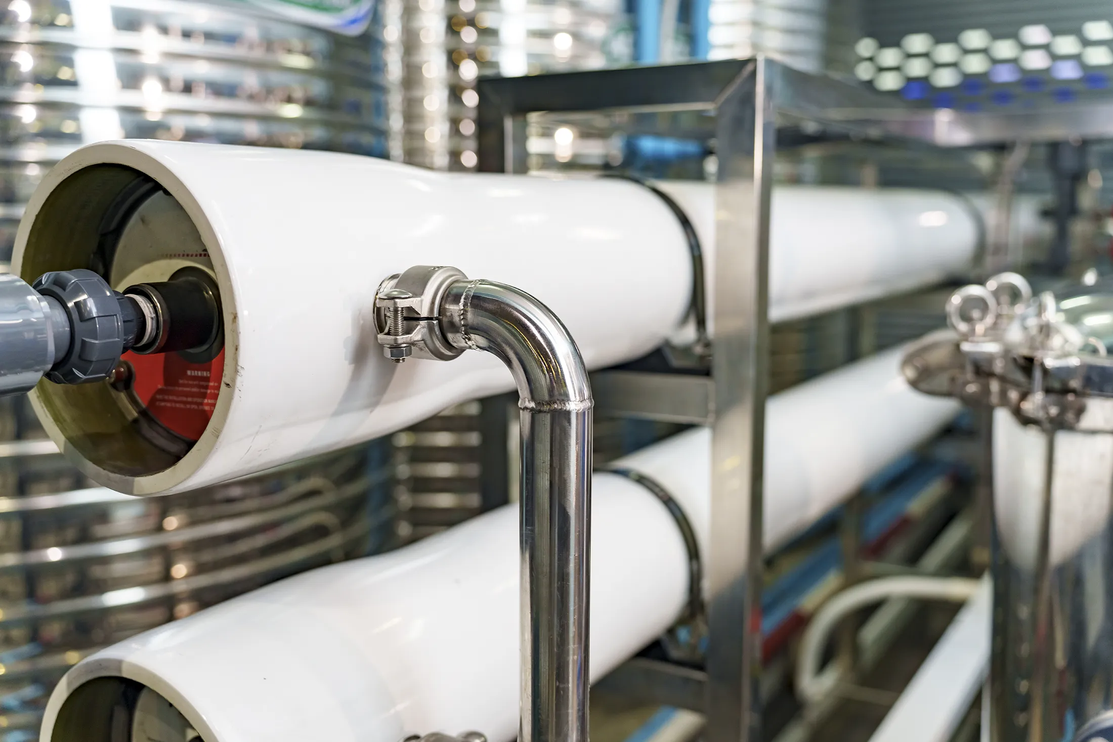 Close-up of industrial-grade reverse osmosis water filtration system with stainless steel pipes and pressure vessels.