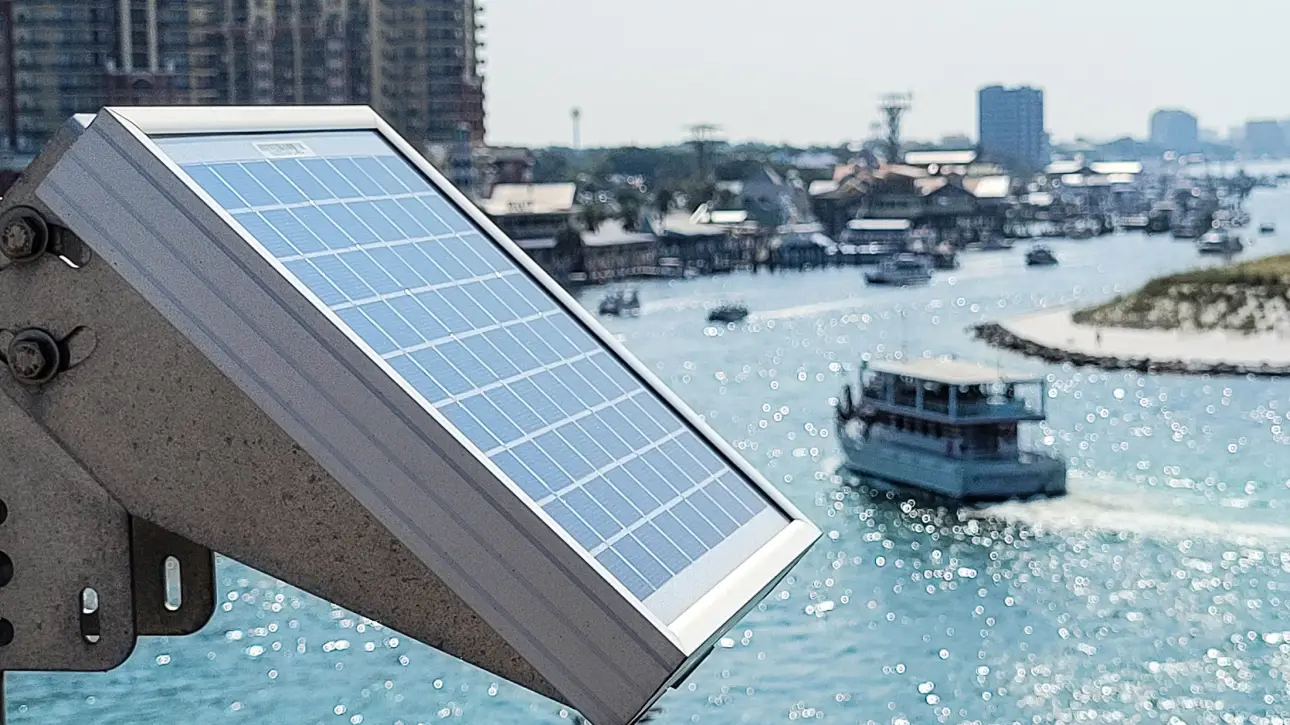 Solar panel capturing sunlight near a marina with boats on the water, illustrating renewable energy use for marine and coastal applications.