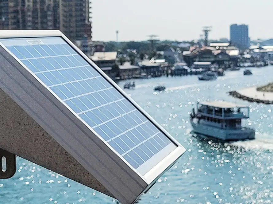 Solar panel capturing sunlight near a marina with boats on the water, illustrating renewable energy use for marine and coastal applications.