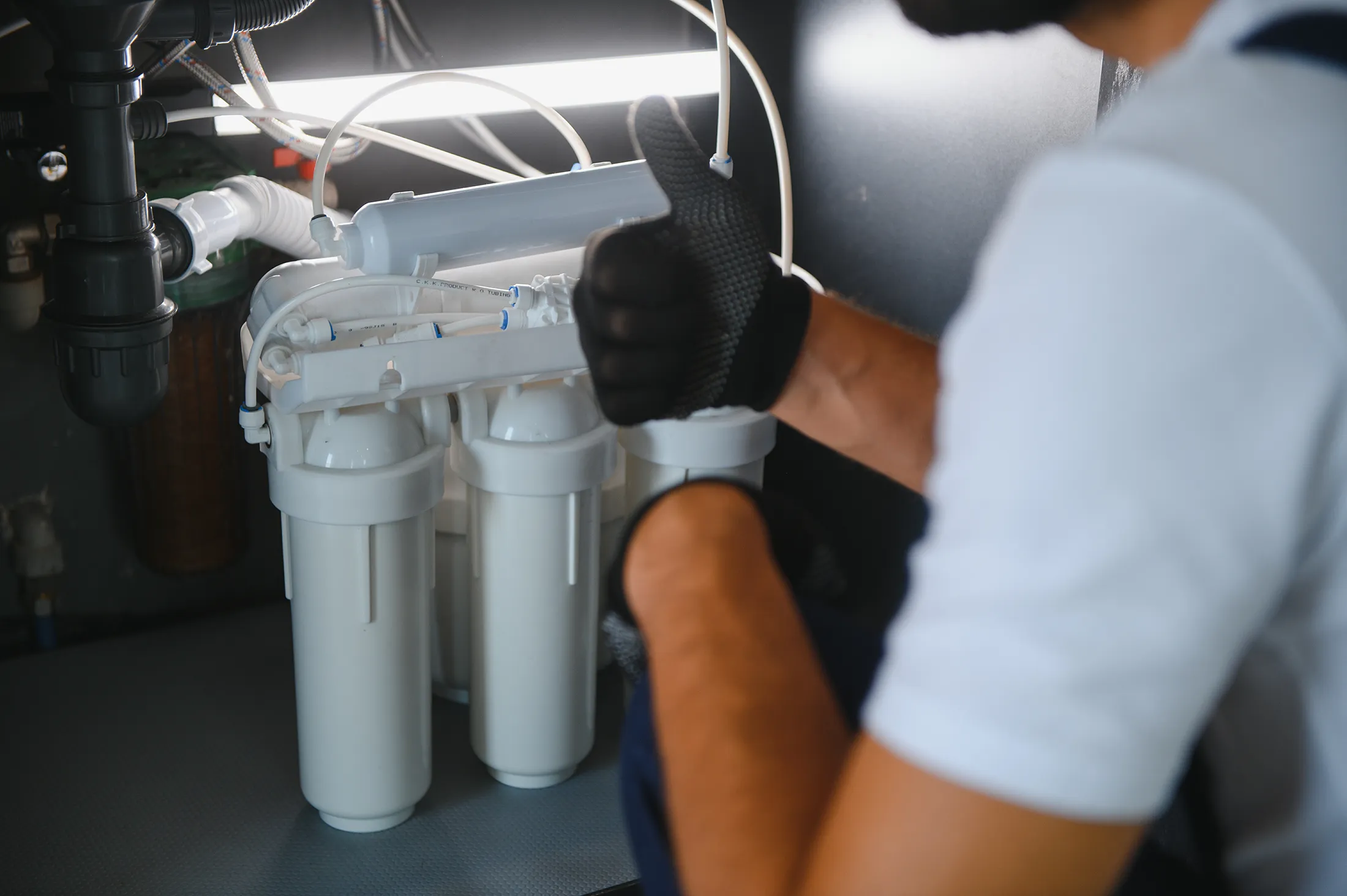plumber-change-the-water-filter-2025-03-17-15-48-08-utc Technician giving a thumbs up while installing a reverse osmosis water filtration system under a sink.