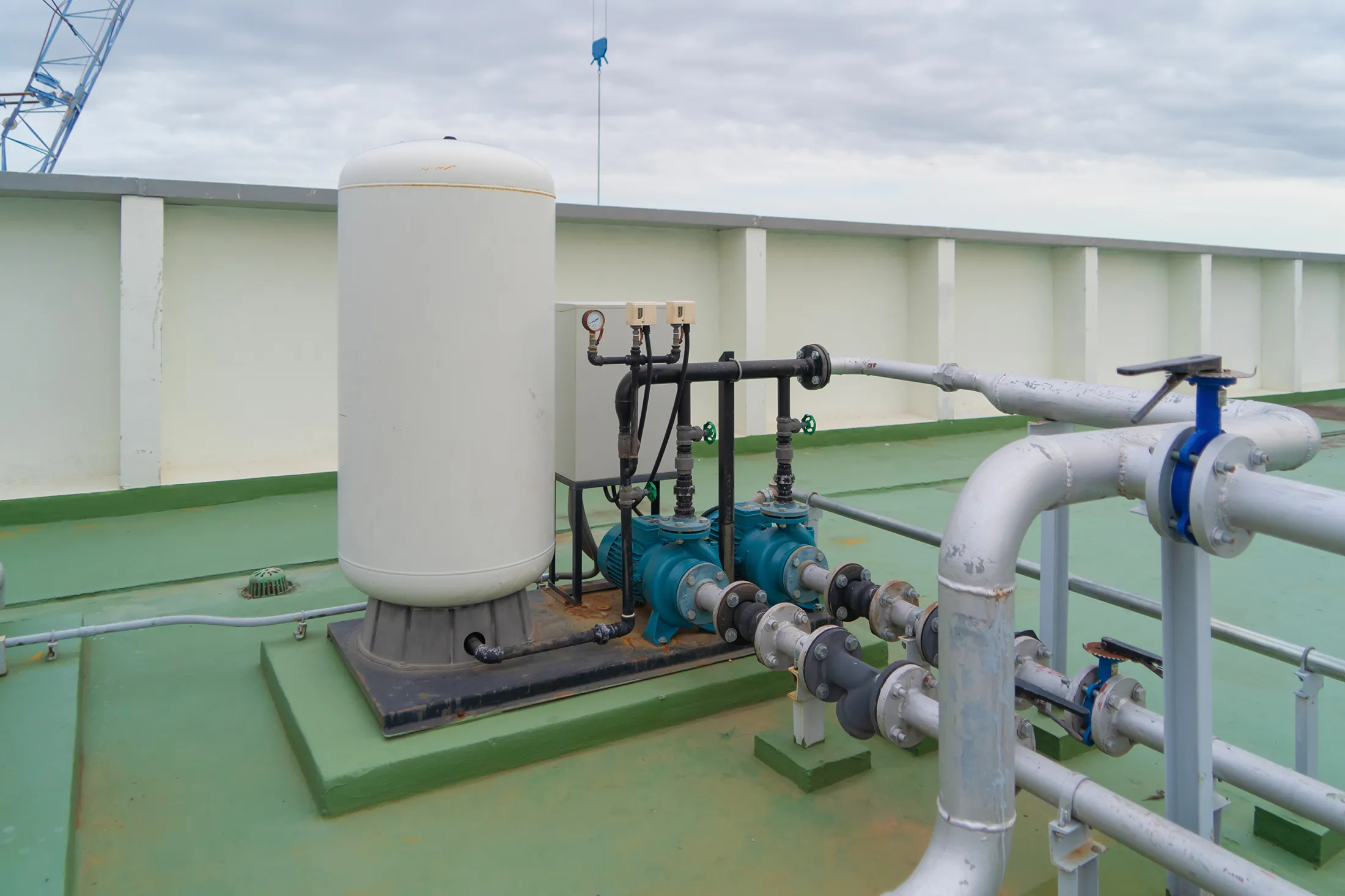 industry-factory-cooling-tower-in-building-syste-2024-10-18-17-39-45-utc Marine desalination system installed on a boat deck with water storage tank, pumps, pipes, and valves used for onboard freshwater production.